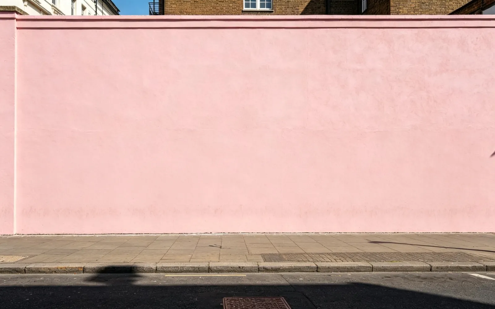 Transeúntes, un patinete y unas papeleras borrados delante de una pared rosa — Después