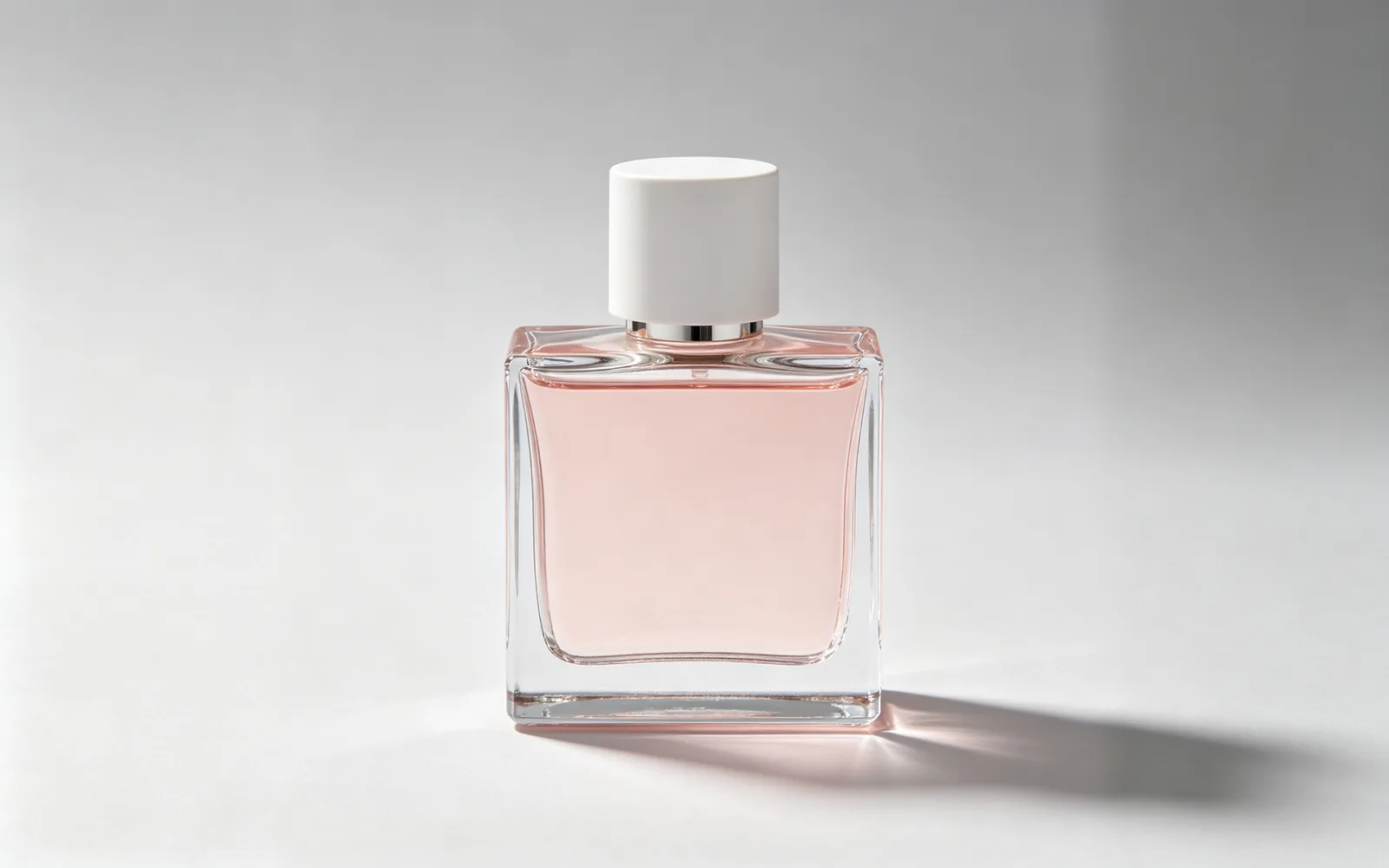Una foto cuadrada de un perfume extendida sobre un fondo de estudio ancho