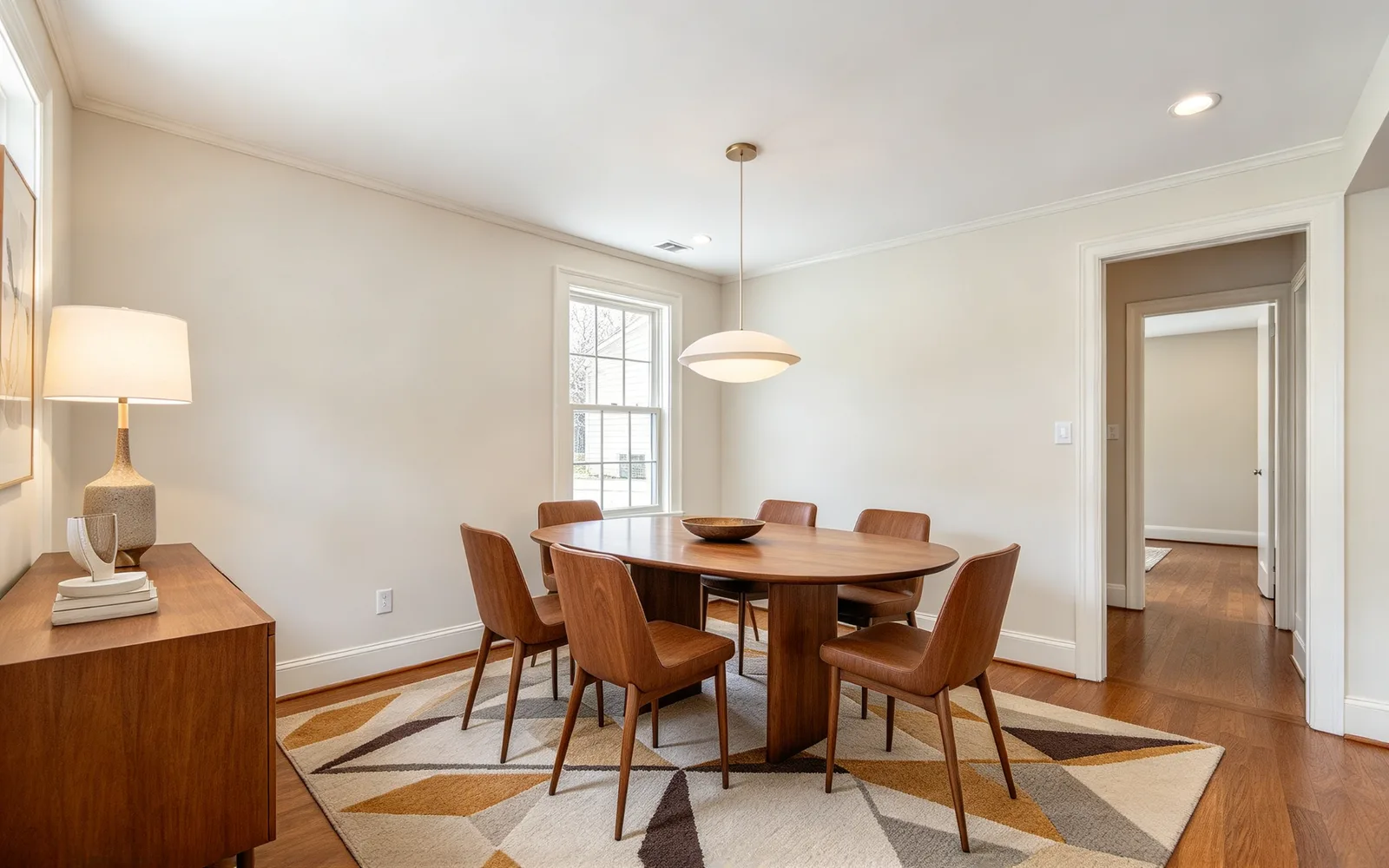 An empty dining room furnished in mid-century style with a table and chairs — After